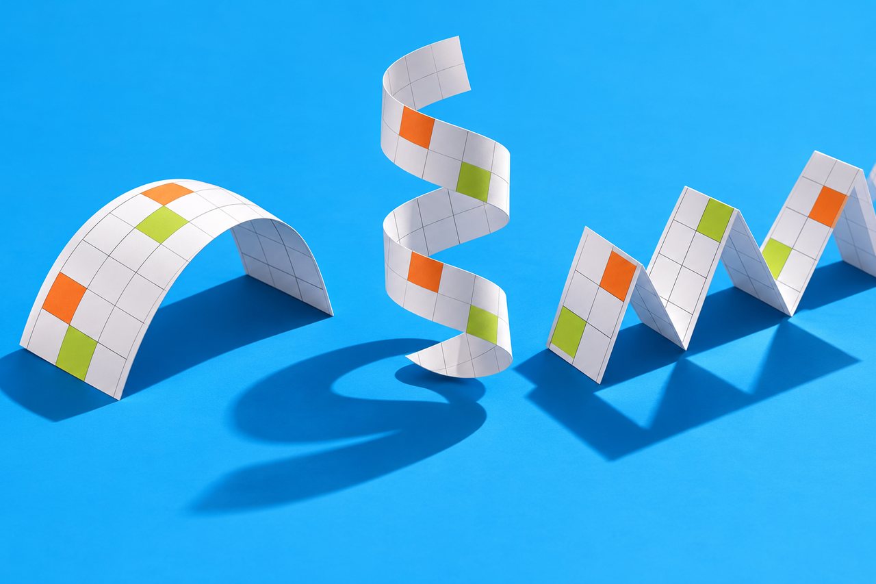 Three paper calendar strips folded into an arch, a spiral and a zigzag on a blue background