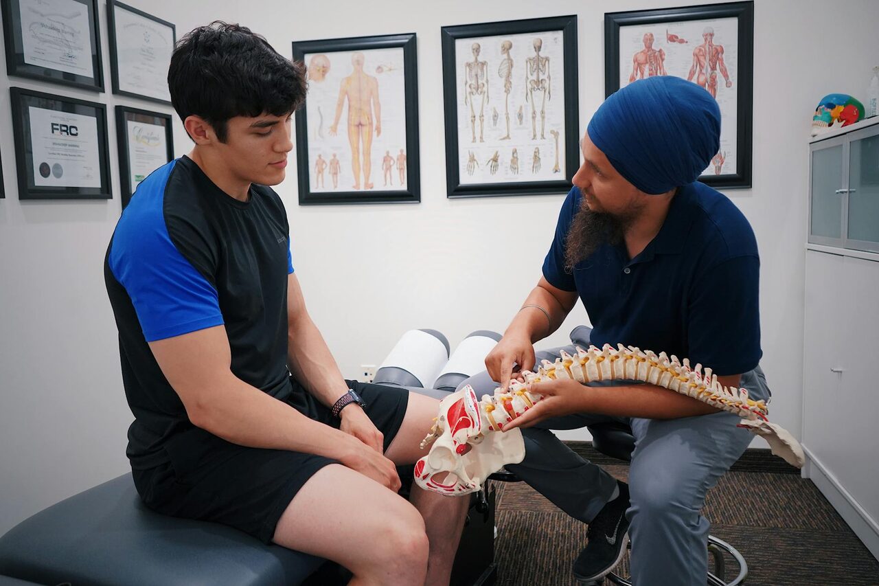 A clinician showing a patient a model of the spine during a consultation